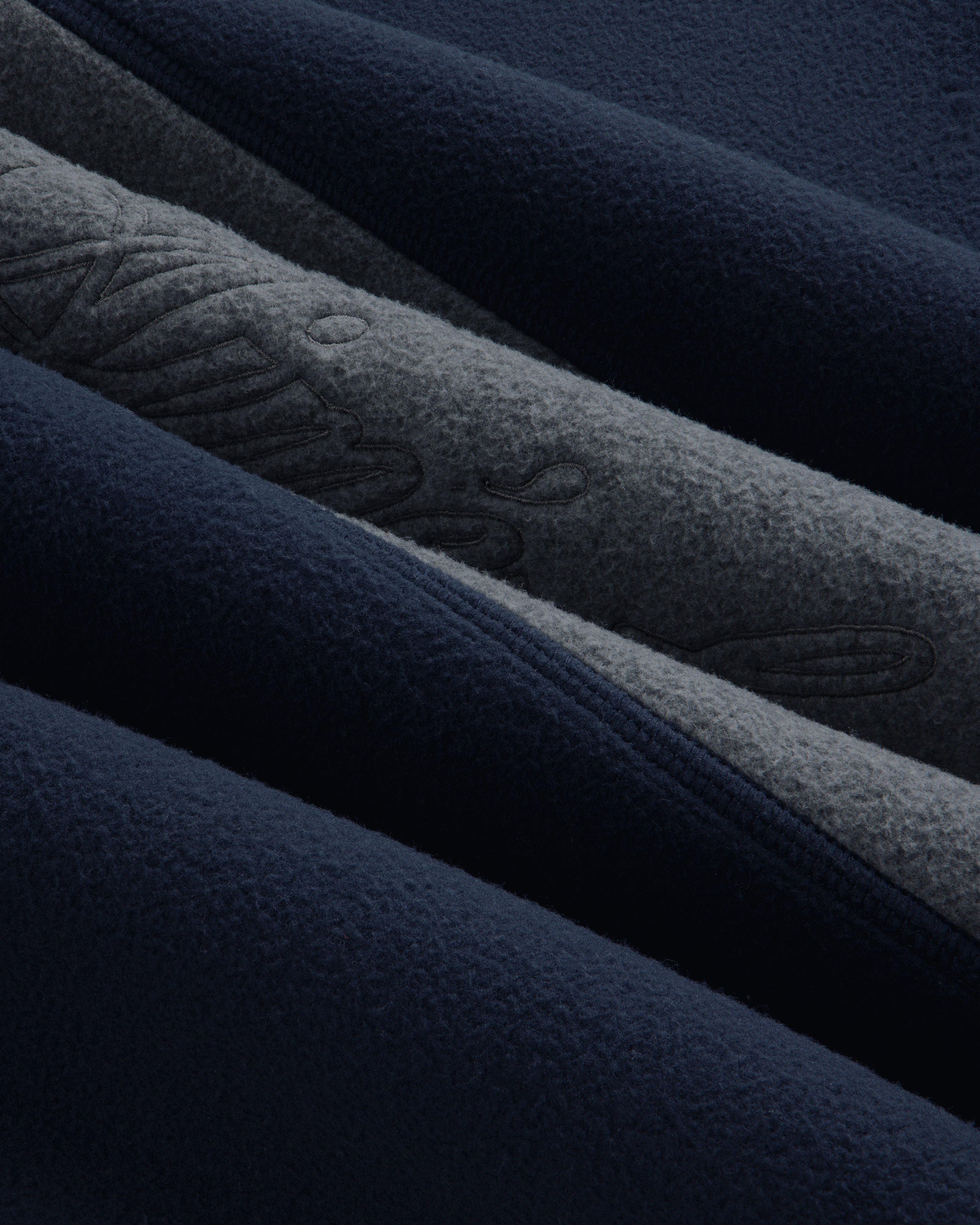 Close-up of a navy and grey Fleece Script Paneled Crewneck Sweatshirt with embroidered script detailing.