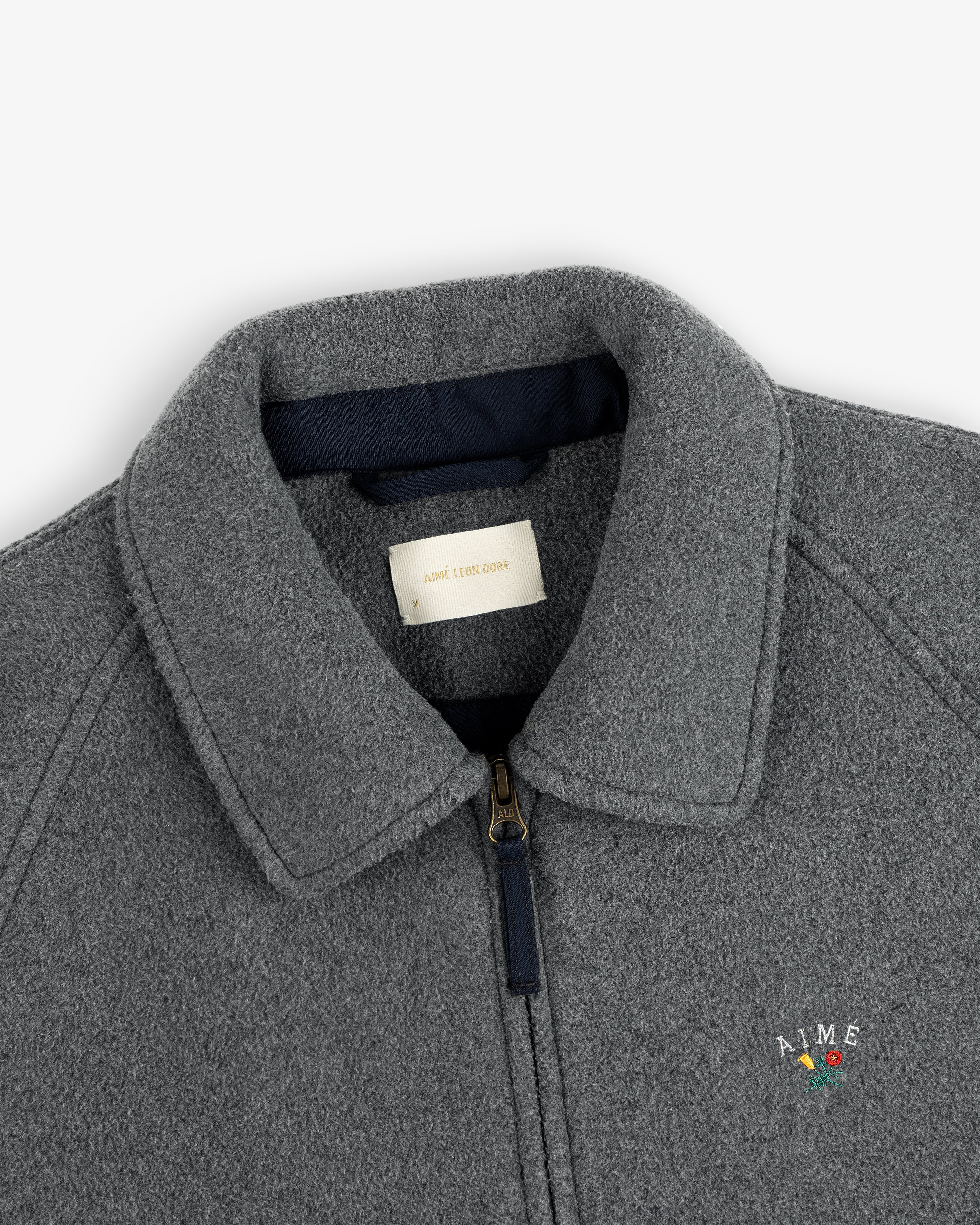 Close-up of a gray Crest Fleece Casual Jacket with collar, zipper, and small AIME chest logo.