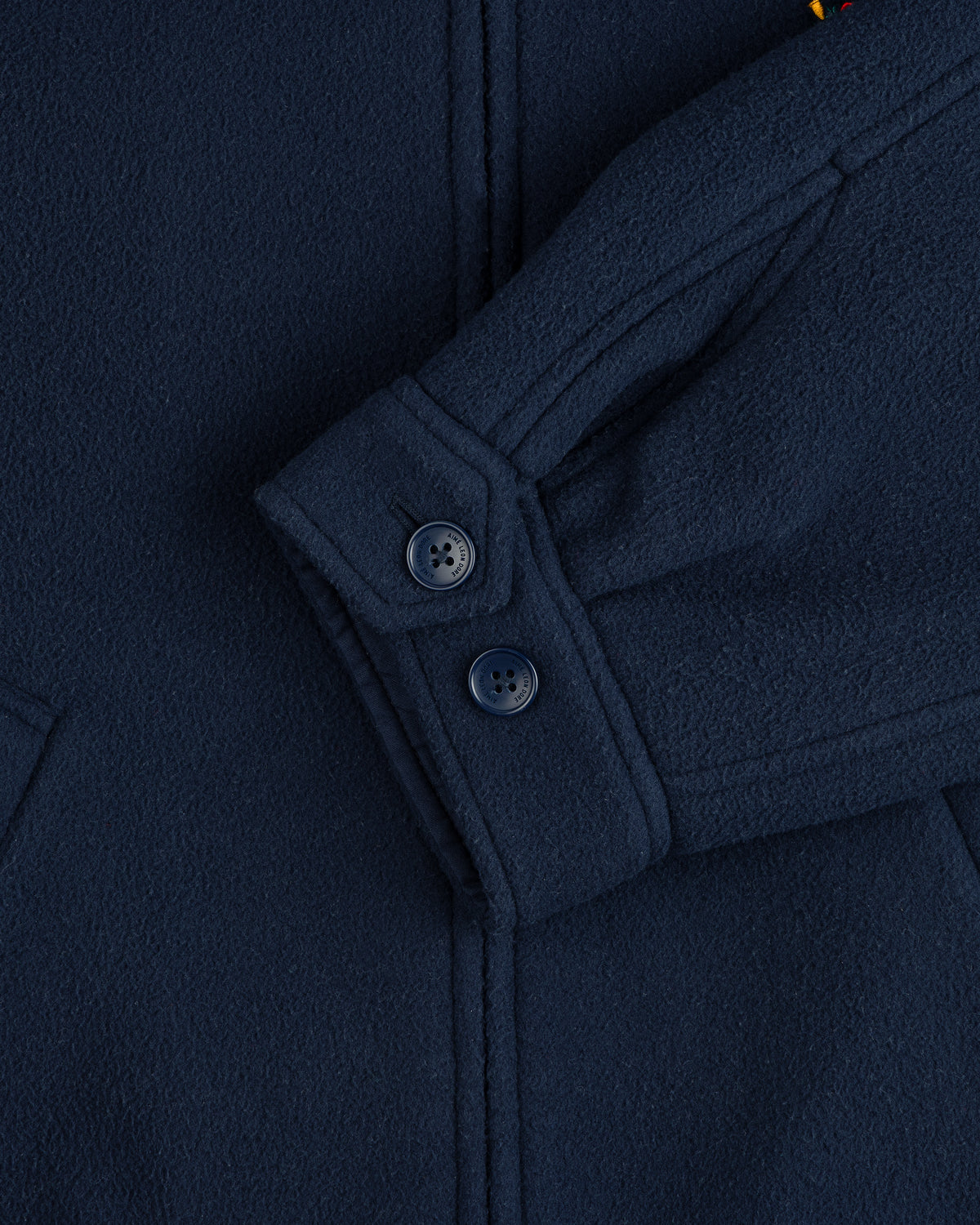 Close-up of Crest Fleece Casual Jacket in navy blue, showing two sleeve buttons and part of the pocket seam.