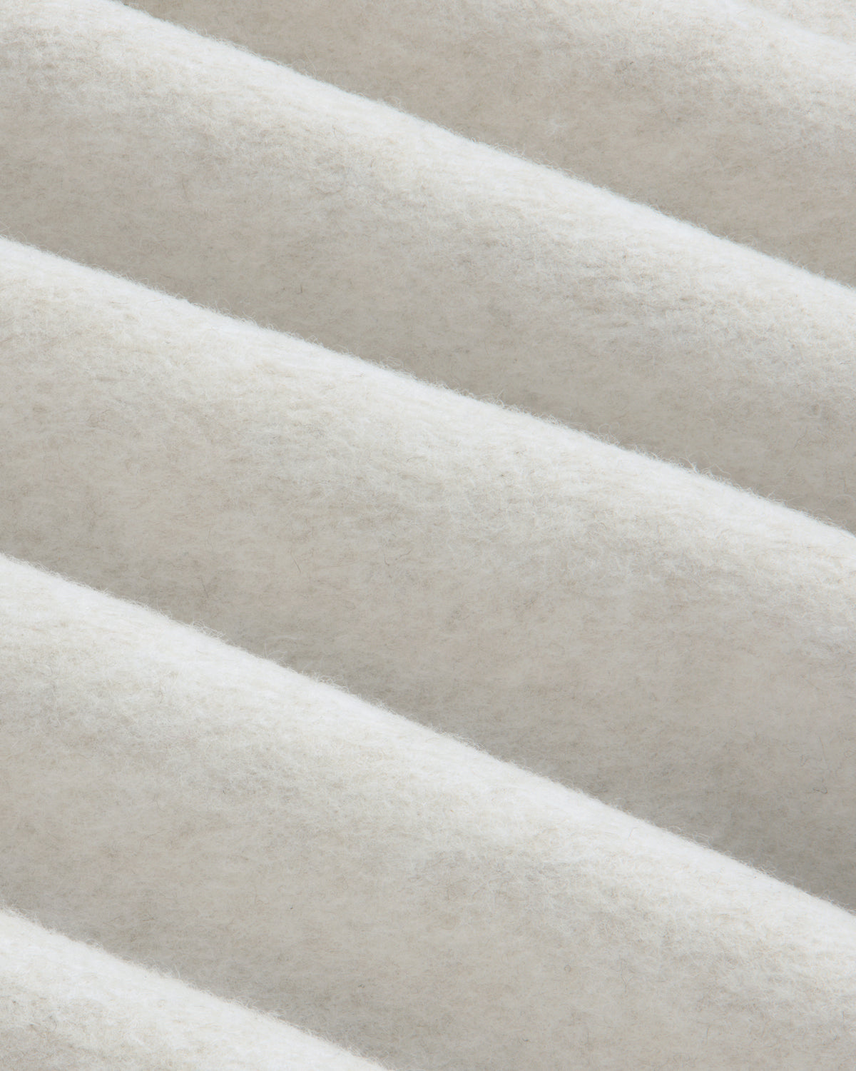 Close-up of folds in the off-white fleece fabric of a Surplus Fleece Quarter Zip Pullover.