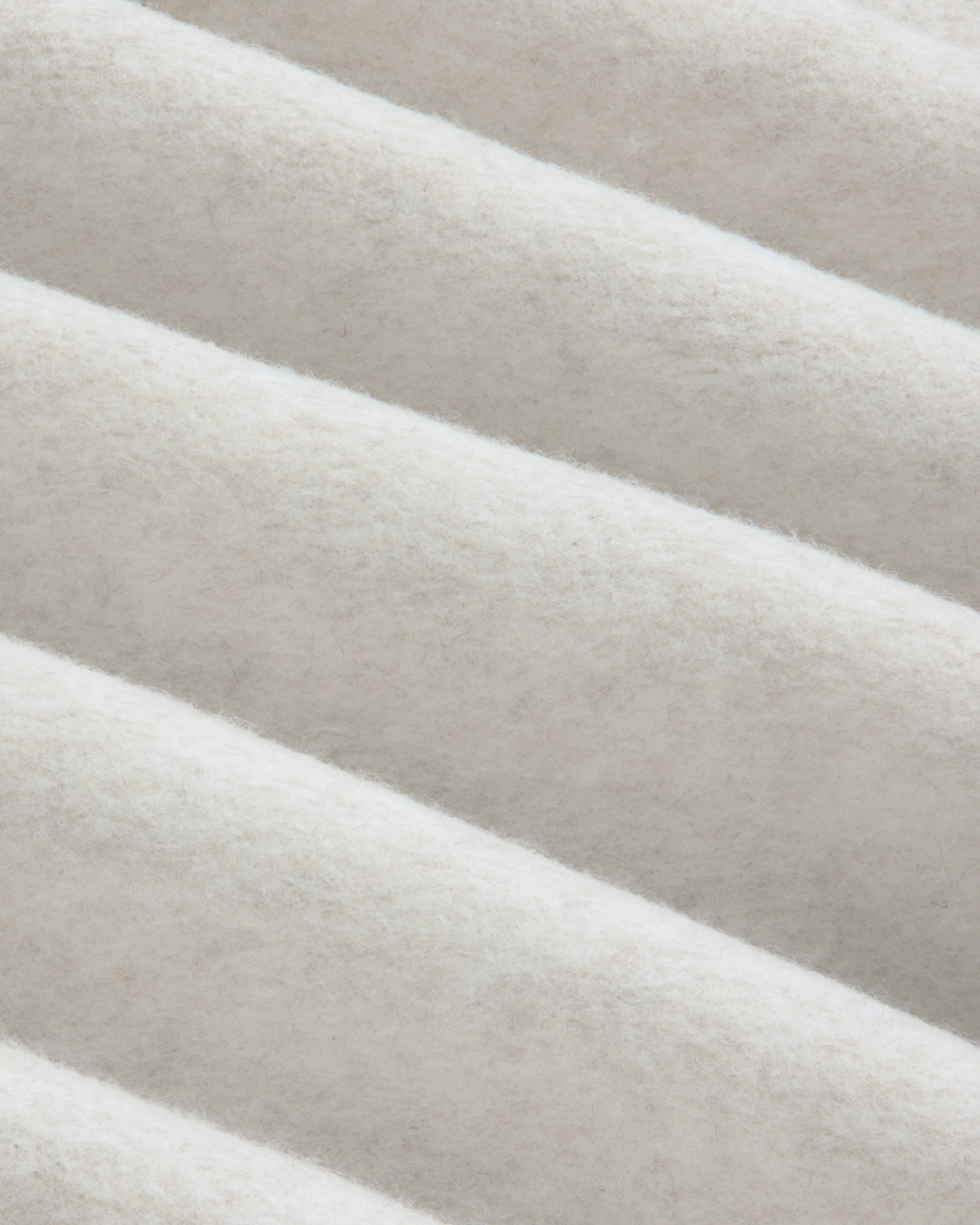 Close-up of folds in the off-white fleece fabric of a Surplus Fleece Quarter Zip Pullover.