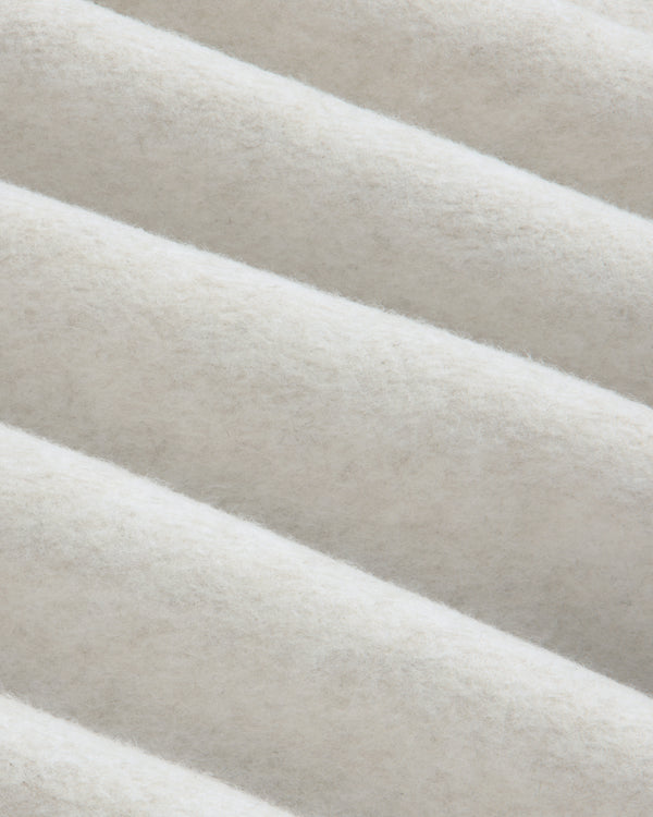 Close-up of folds in the off-white fleece fabric of a Surplus Fleece Quarter Zip Pullover.