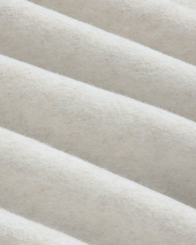 Close-up of folds in the off-white fleece fabric of a Surplus Fleece Quarter Zip Pullover.