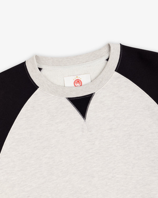 ALD / Olympiacos F.C. Colorblock Crewneck Sweatshirt in light gray with black raglan sleeves and a V-stitch collar.