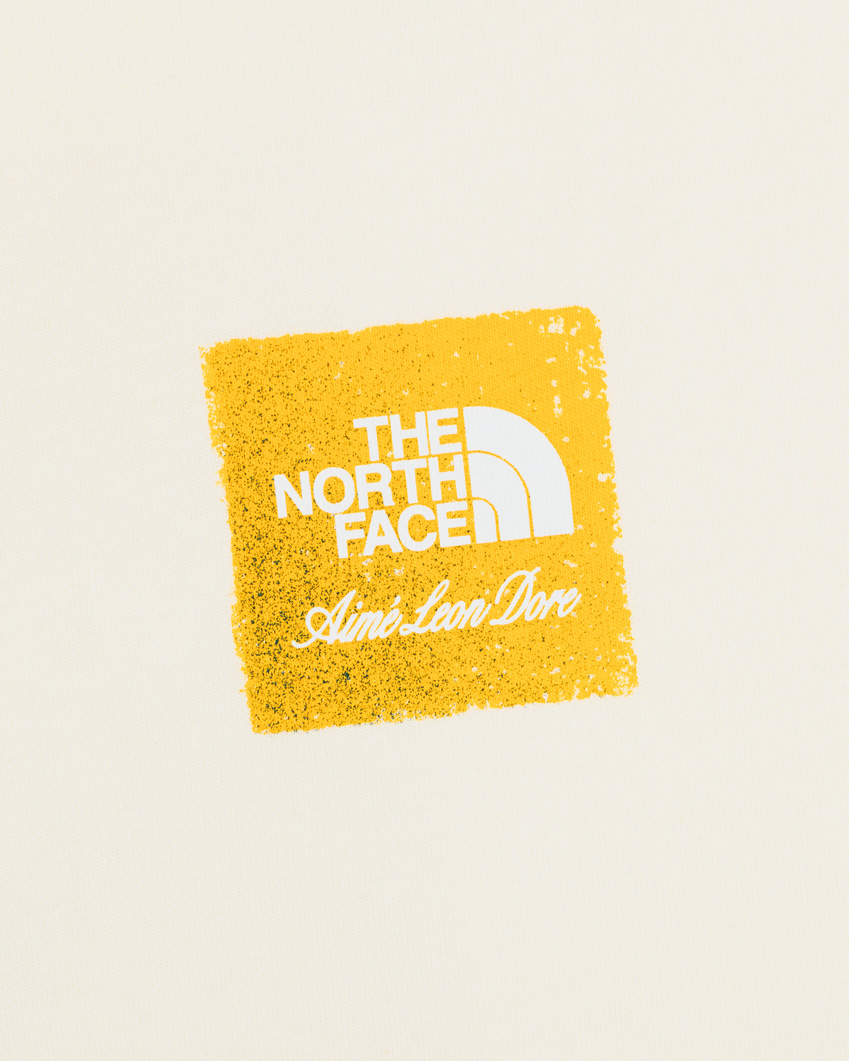 Cream-colored ALD / The North Face Logo Tee with a yellow square and white text.