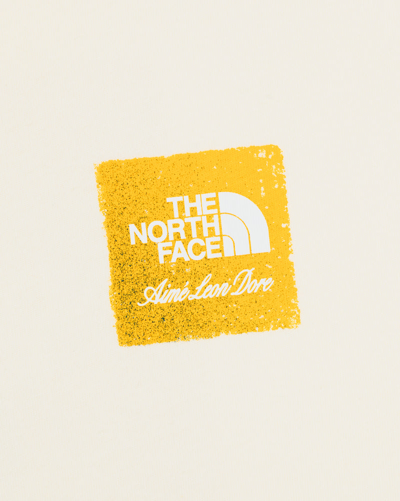 Cream-colored ALD / The North Face Logo Tee with a yellow square and white text.