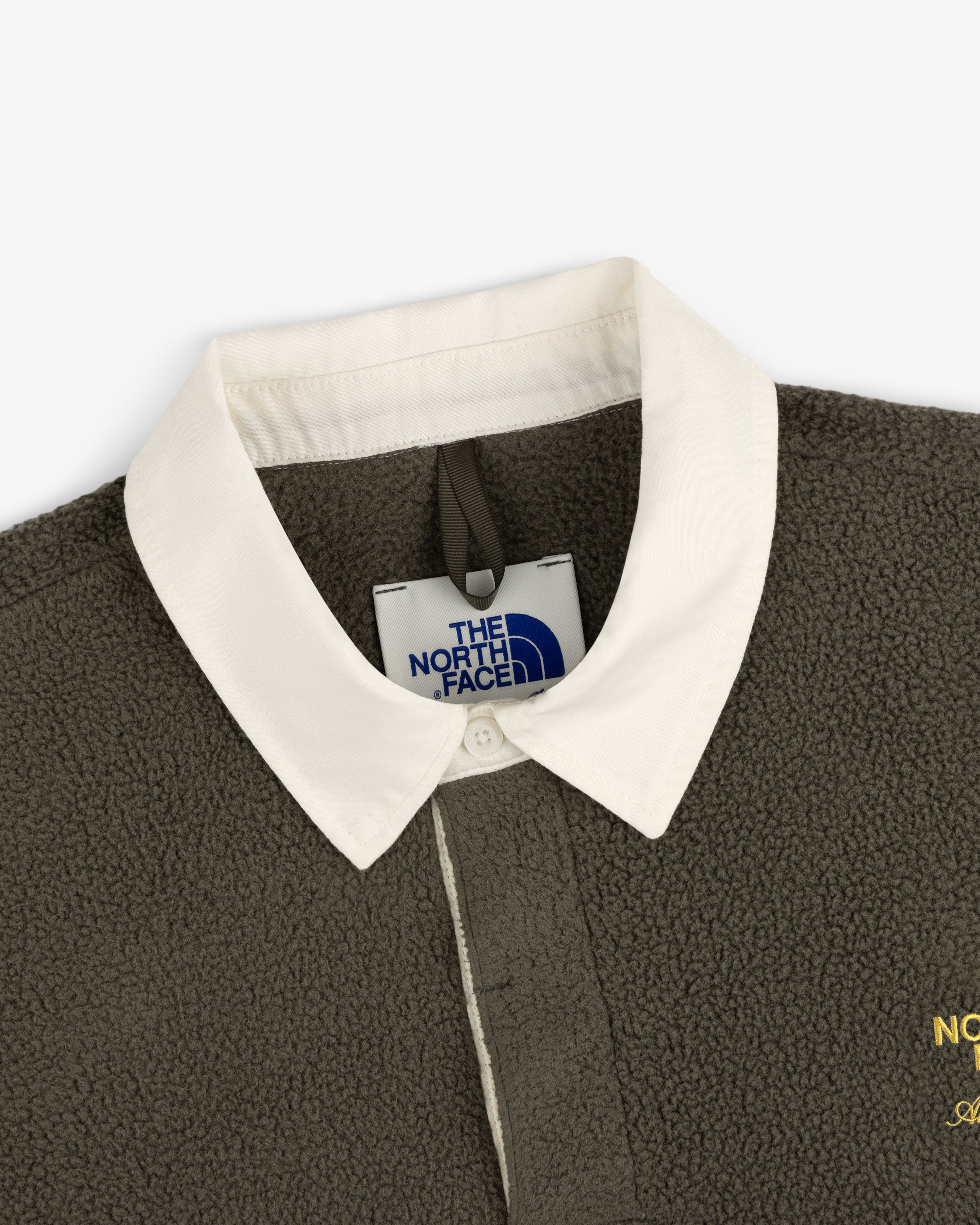 Close-up of ALD / The North Face Fleece Rugby in olive green with a white collar, showing the brand tag and collar.