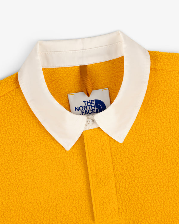 Close-up of yellow ALD / The North Face Fleece Rugby with white collar and visible brand tag.