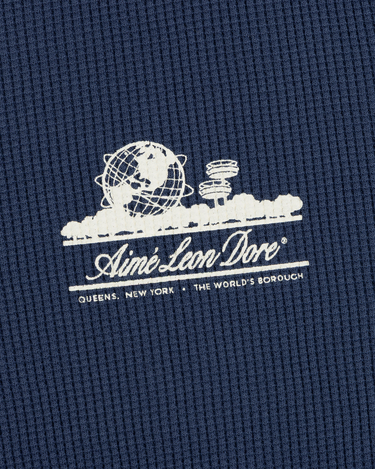 White Aimé Leon Dore globe logo on blue Long-Sleeve Unisphere Waffle Thermal; text below: Queens, New York.