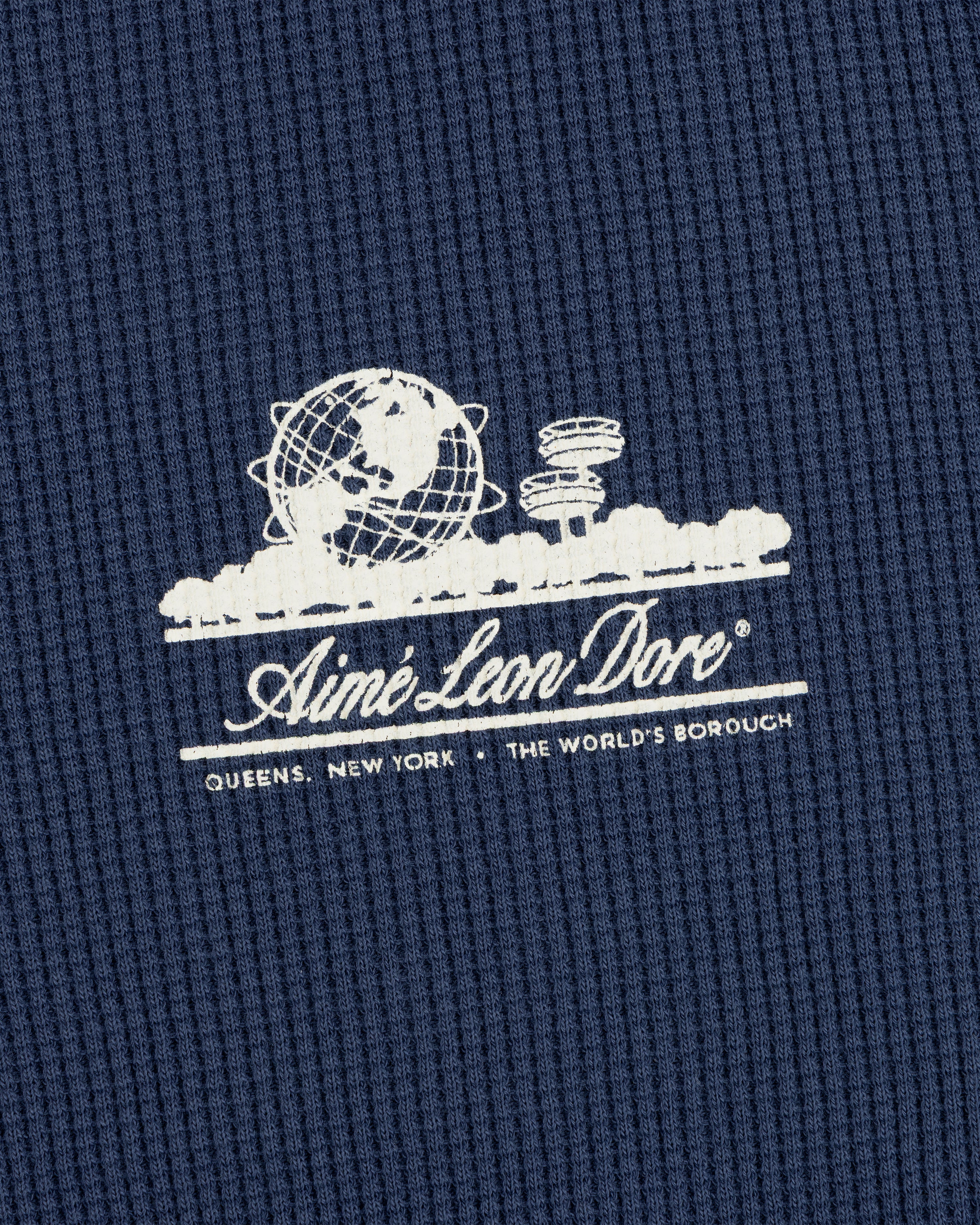 White Aimé Leon Dore globe logo on blue Long-Sleeve Unisphere Waffle Thermal; text below: Queens, New York.