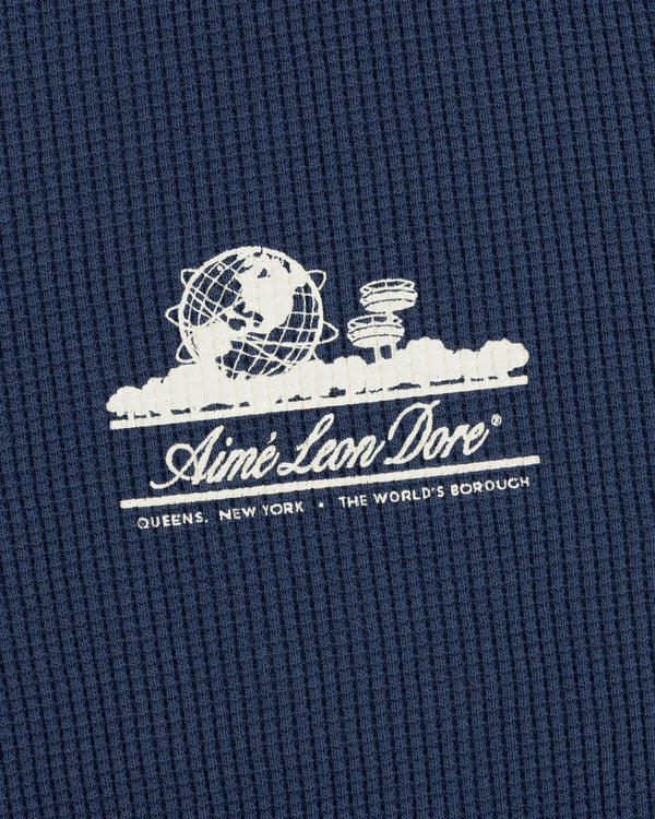 White Aimé Leon Dore globe logo on blue Long-Sleeve Unisphere Waffle Thermal; text below: Queens, New York.