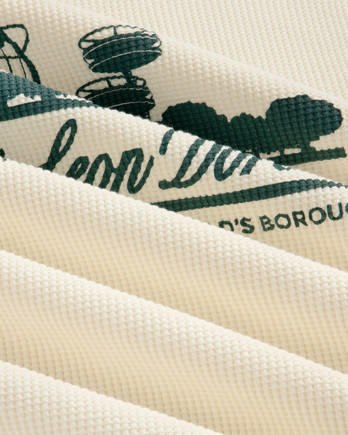 Cream waffle thermal with green Unisphere print, shown close-up with soft folds and ribbed texture.