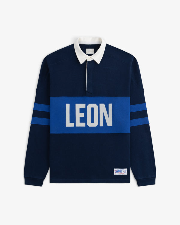 Leon Dore Collegiate Rugby—navy shirt with white collar, blue sleeve stripes, and bold LEON chest print.