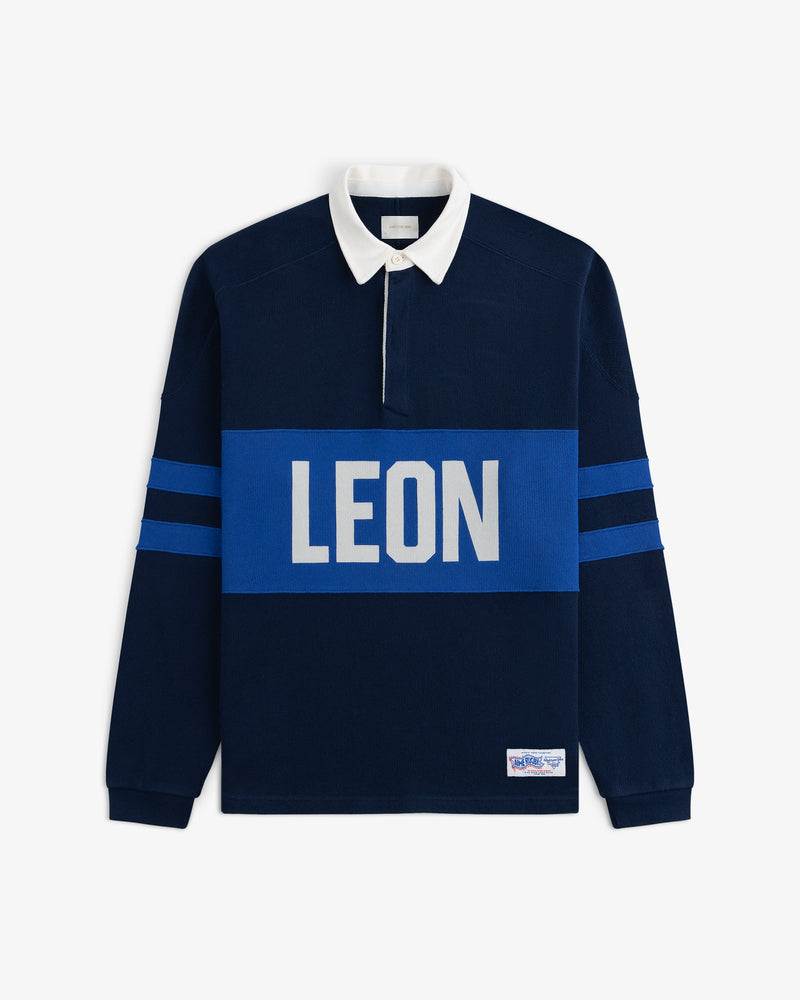 Leon Dore Collegiate Rugby—navy shirt with white collar, blue sleeve stripes, and bold LEON chest print.