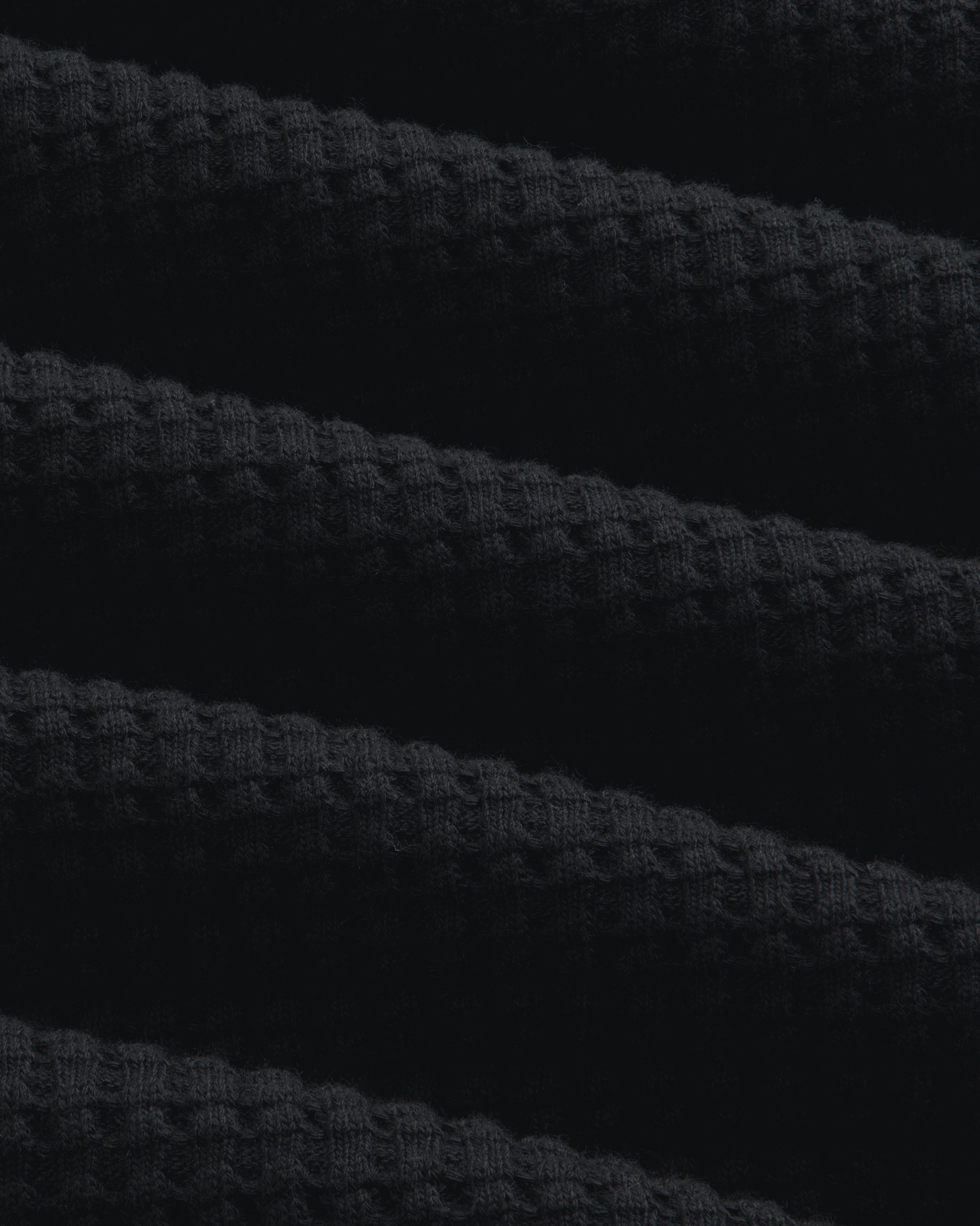 Close-up of black Long-Sleeve Waffle Thermal fabric with a textured waffle-knit pattern.