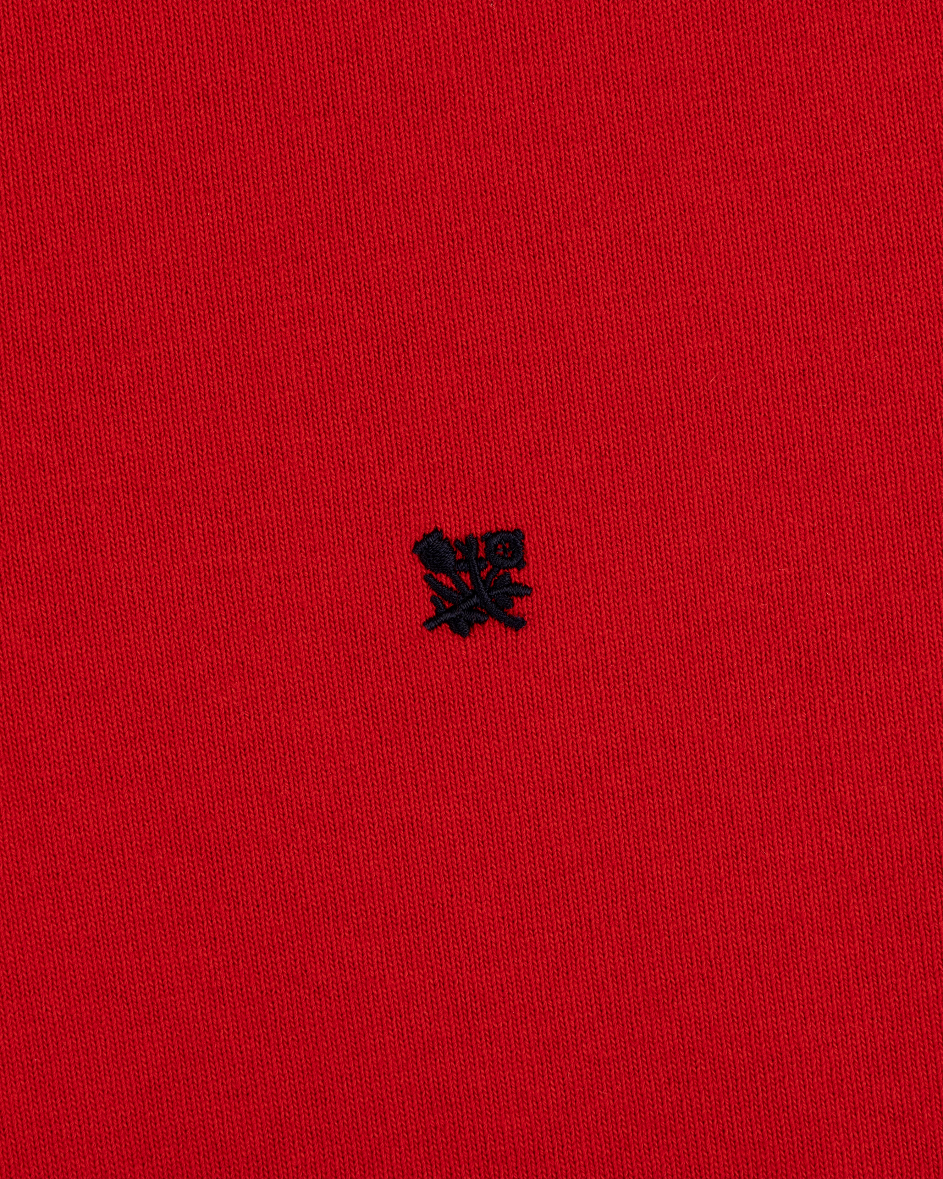 Red “Crest Rugby” fabric with a small, detailed black embroidered emblem at the center.