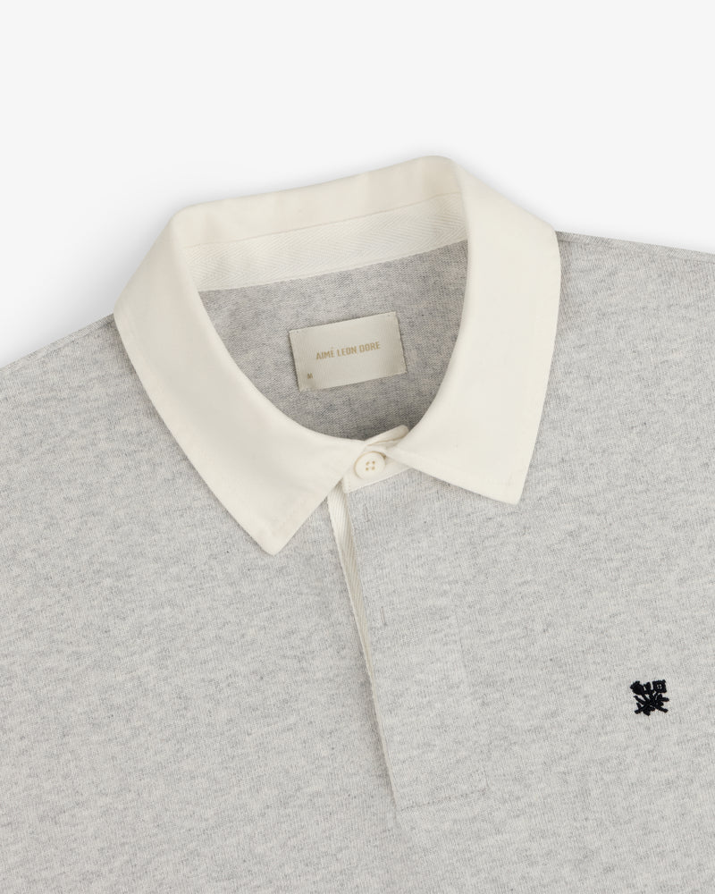Crest Rugby: Light gray rugby shirt with white collar, single button, and small black chest logo.