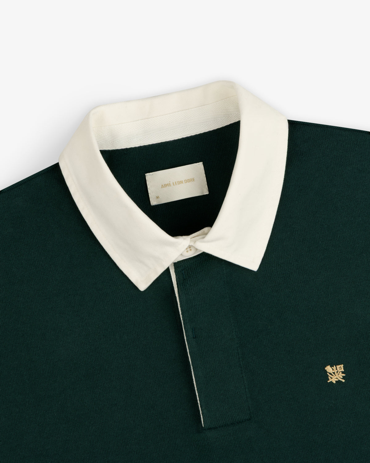 Crest Rugby: Dark green polo with white collar, yellow chest logo.