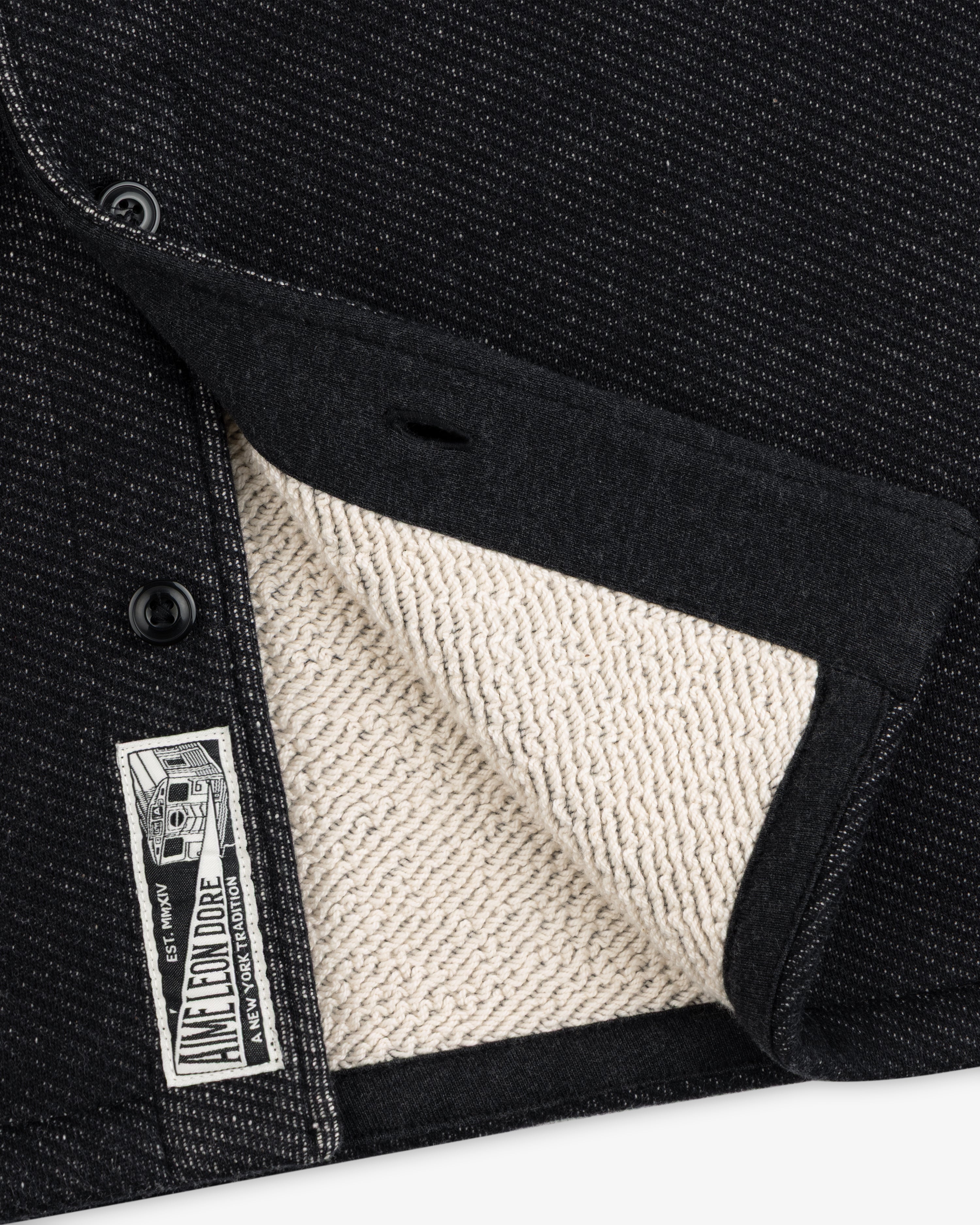 Close-up of a black Terry Lounge shirt with a textured, beige terry cloth interior and a branded label at the hem.