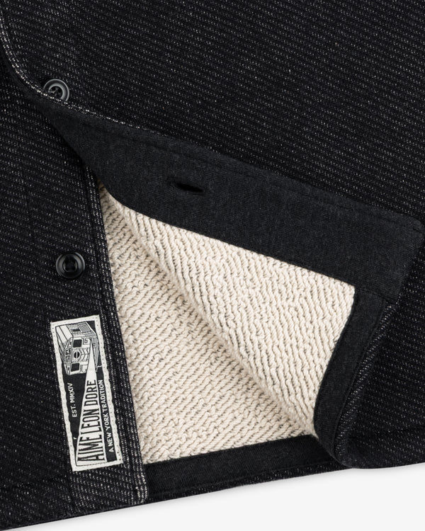 Close-up of a black Terry Lounge shirt with a textured, beige terry cloth interior and a branded label at the hem.