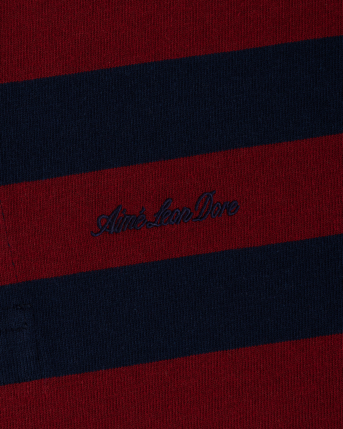 Striped Script Rugby in burgundy and navy blue knit fabric with dark script embroidery in the center.