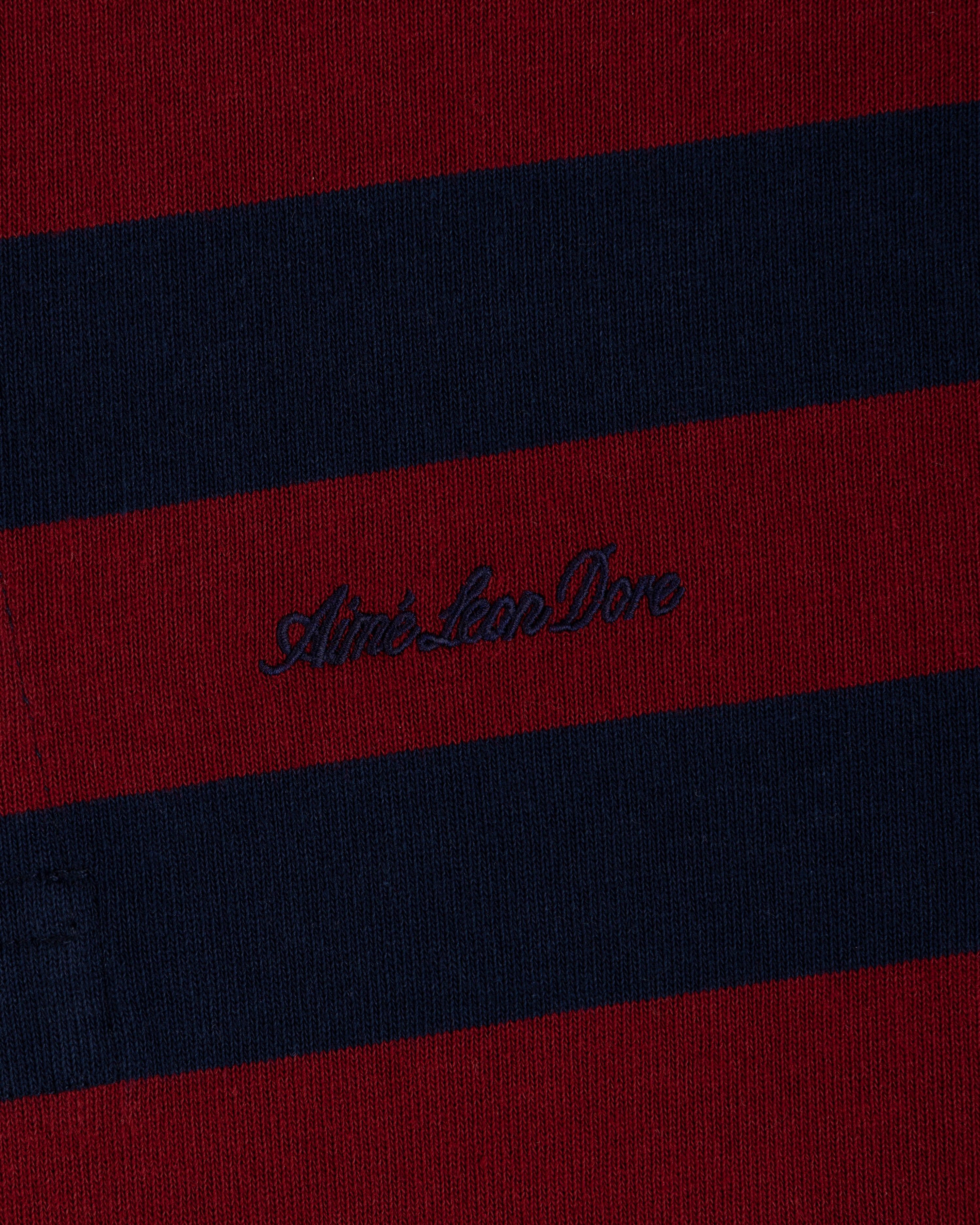 Striped Script Rugby in burgundy and navy blue knit fabric with dark script embroidery in the center.