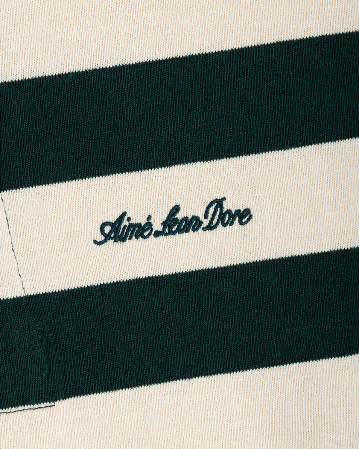 Close-up of a Striped Script Rugby shirt in dark green and off-white with the brand name embroidered in script.