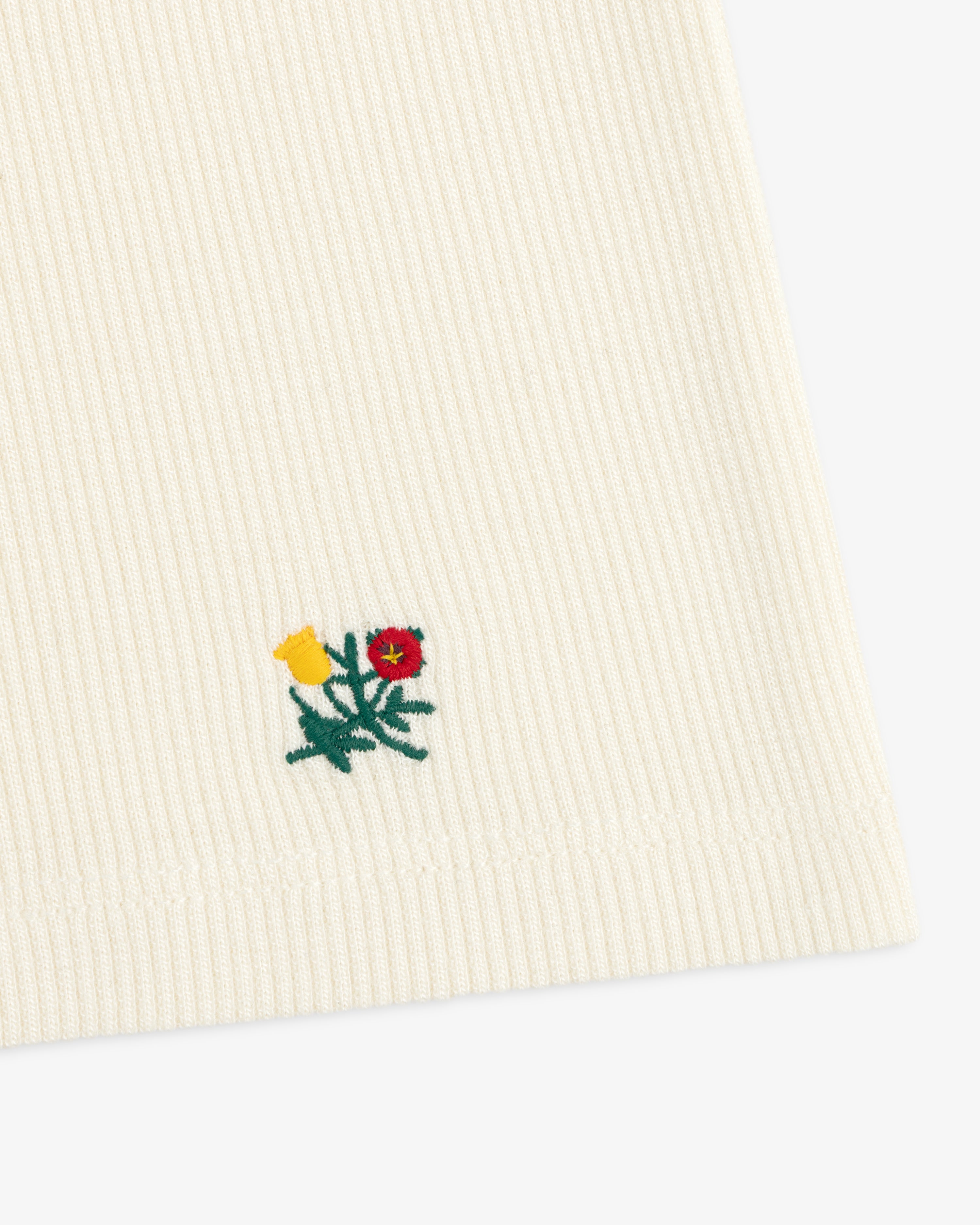 Cream-colored Ribbed Scoop Neck Long-Sleeve Tee with a small embroidered floral design near the hem.