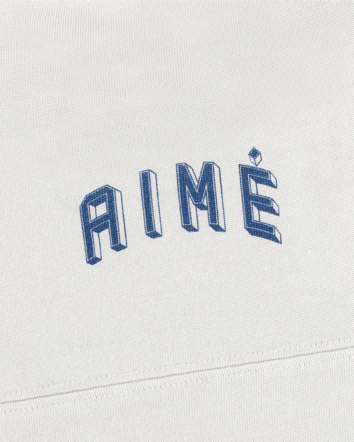 White Football Ringer Tee fabric with the word AIME embroidered in blue, three-dimensional lettering.