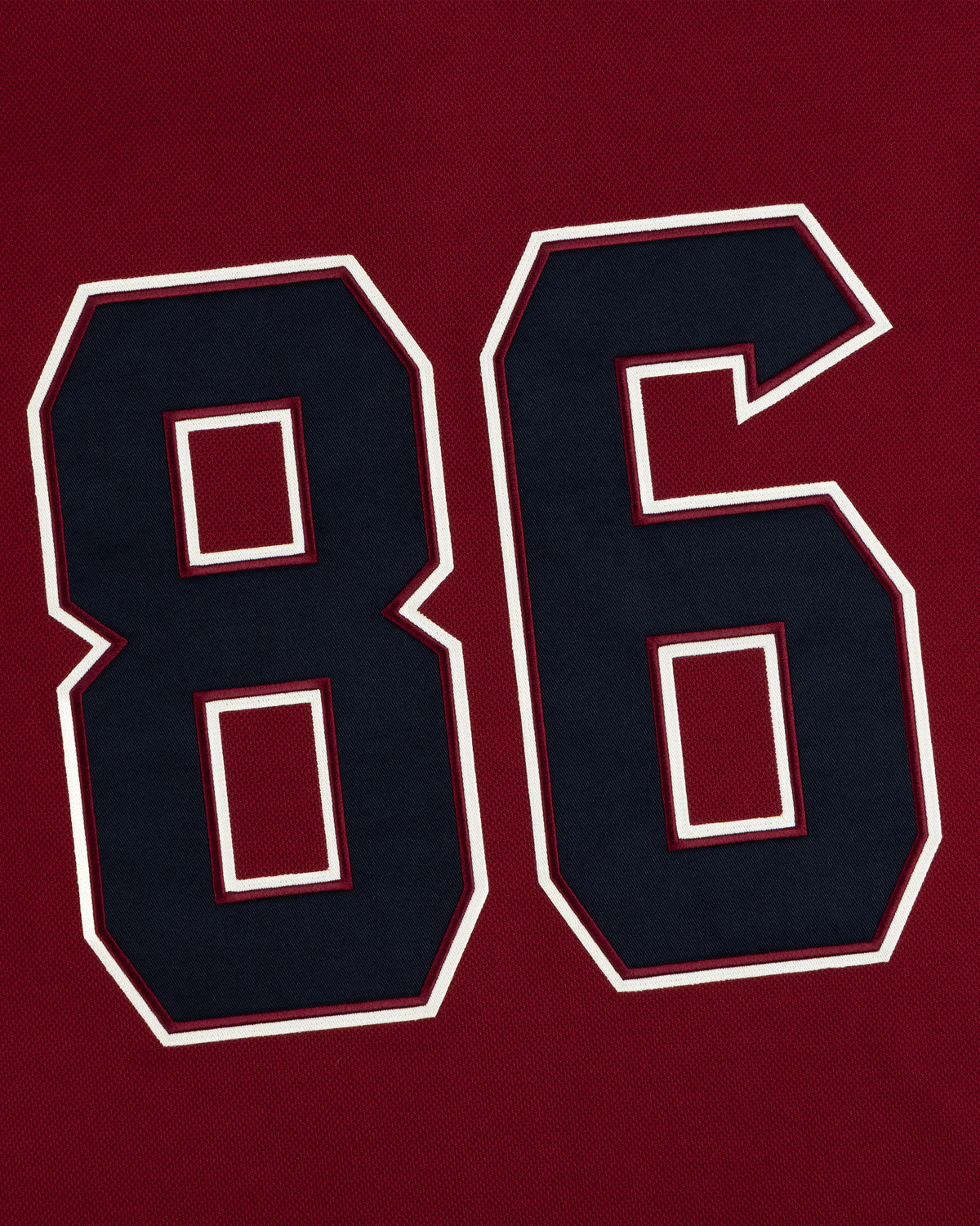 Dark navy number 86 with white and maroon outlines on a dark red Team Aimé Hockey Jersey.