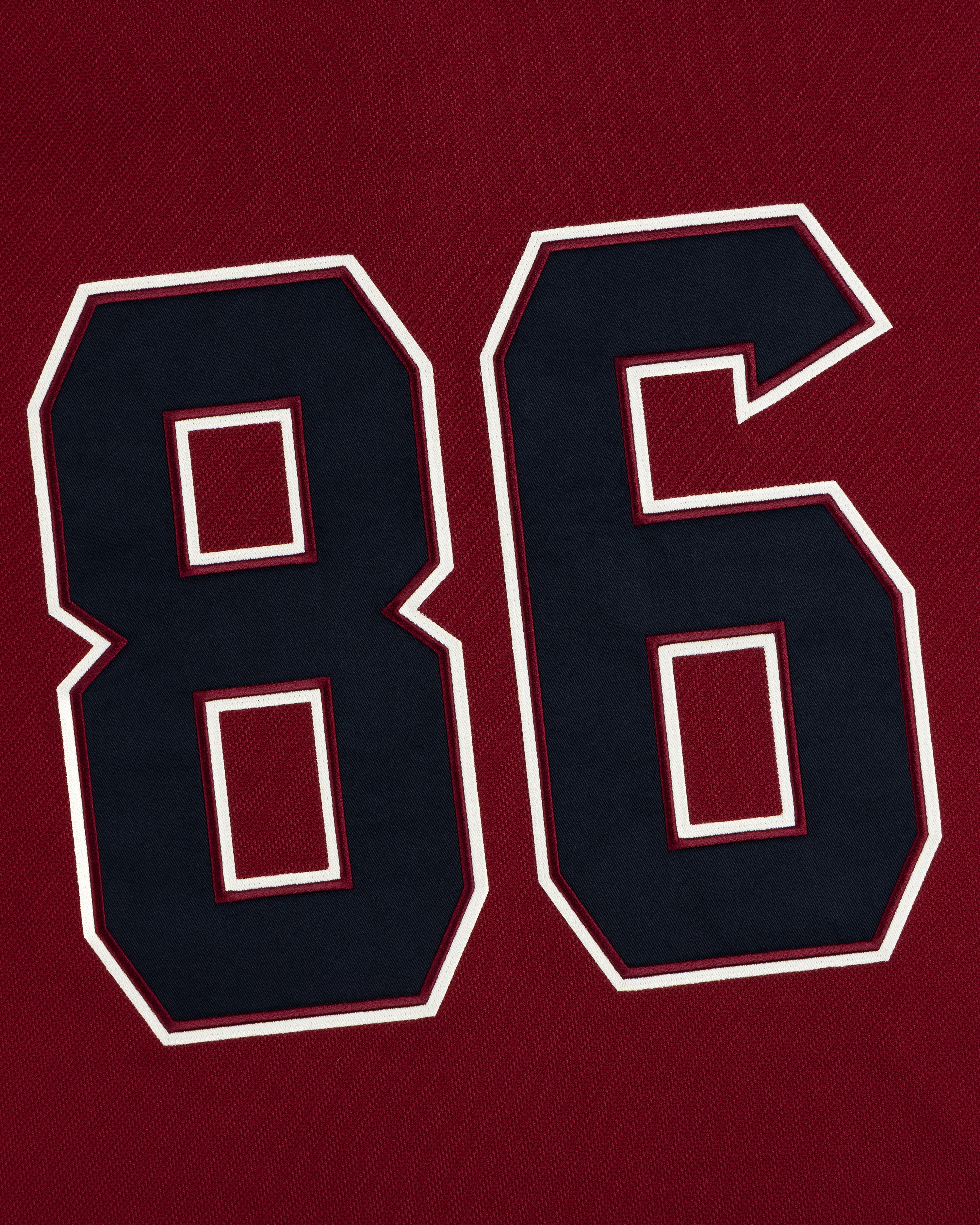 Dark navy number 86 with white and maroon outlines on a dark red Team Aimé Hockey Jersey.