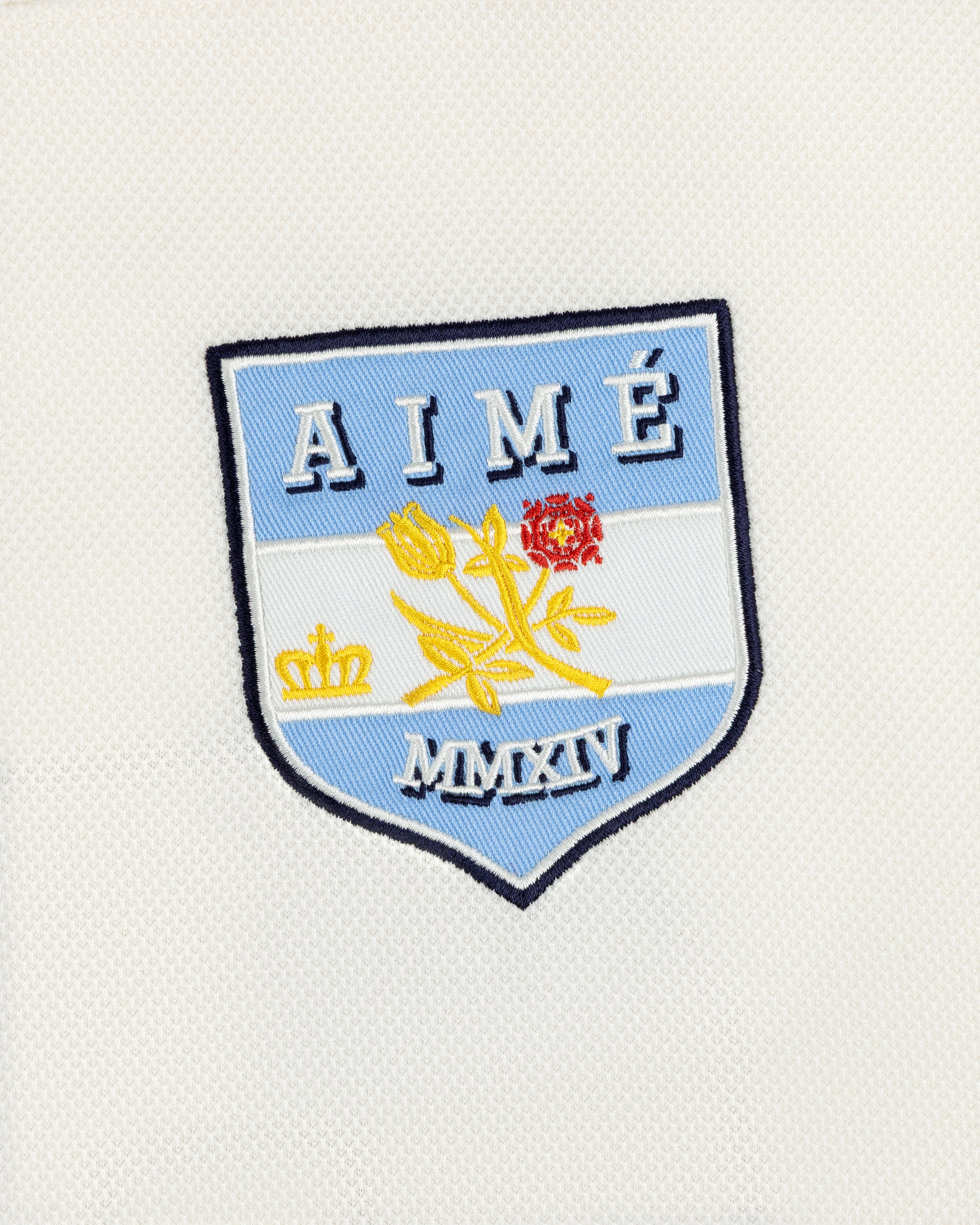 Team Aimé Hockey Jersey featuring an embroidered shield patch with a flower, crown, and the text AIMÉ and MMXIV.
