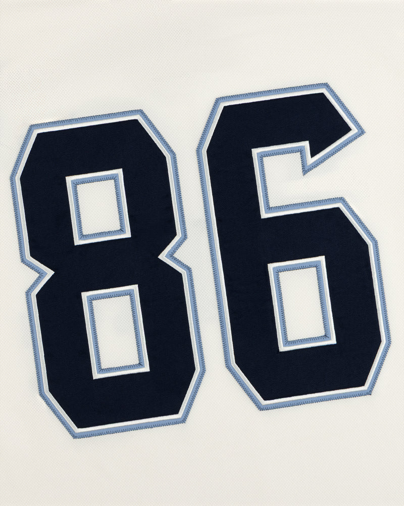The number 86 in dark navy blue with light blue and white outlines on a white Team Aimé Hockey Jersey.