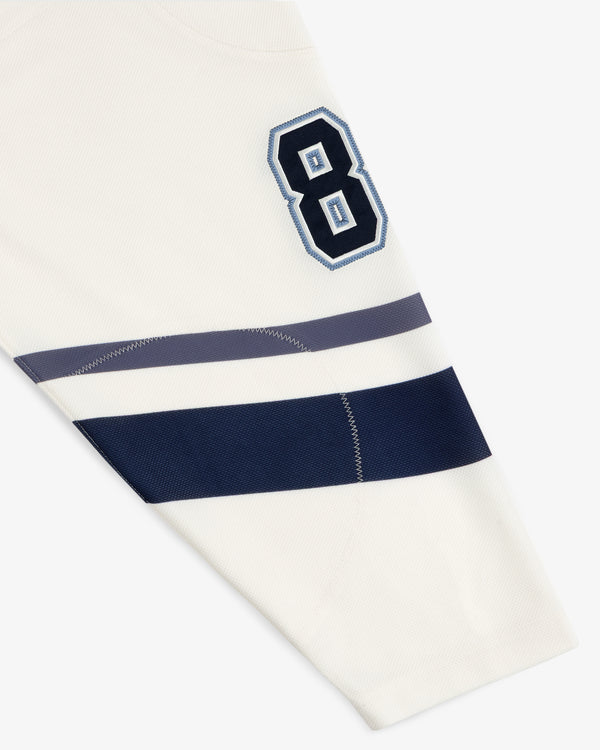 Team Aimé Hockey Jersey sleeve in cream with the number 8 and two horizontal navy and gray stripes.