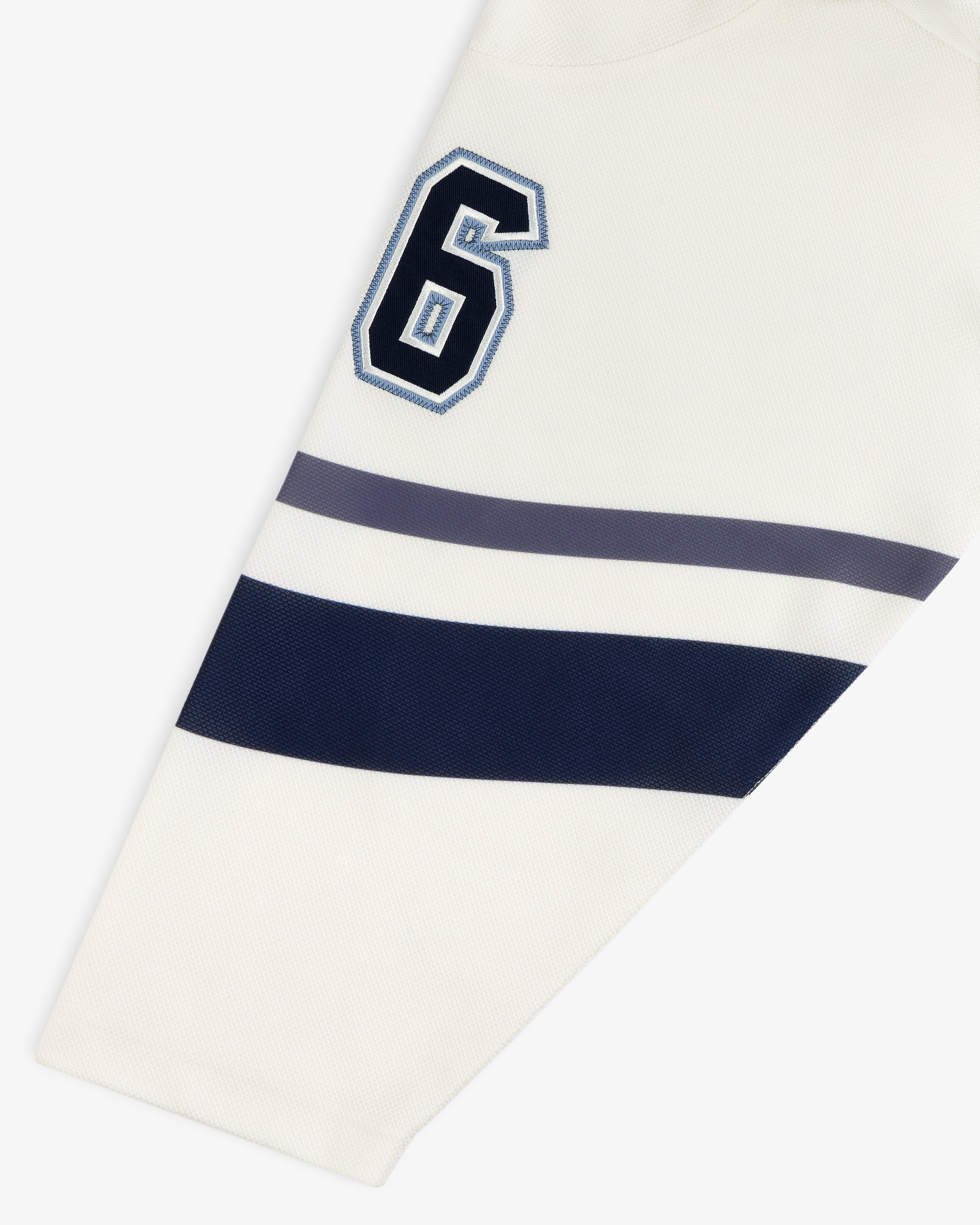 Off-white Team Aimé Hockey Jersey sleeve featuring the number 6 in navy and blue with two matching horizontal stripes.