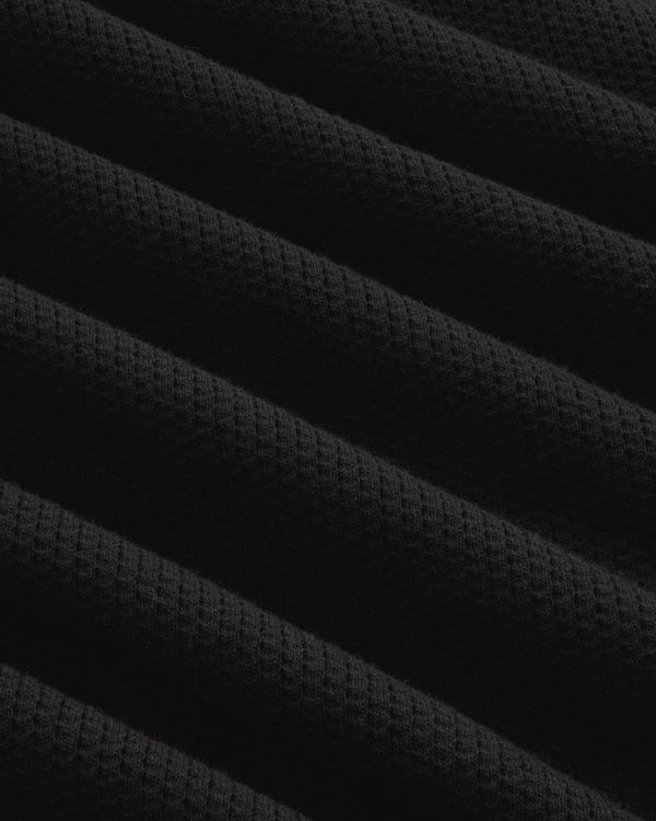 Close-up of black ribbed mesh fabric with diagonal folds on the Long-Sleeve Mesh Football Tee.