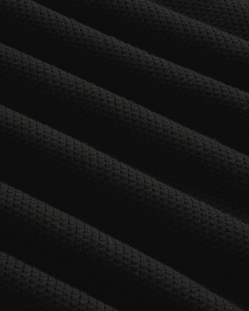 Close-up of black ribbed mesh fabric with diagonal folds on the Long-Sleeve Mesh Football Tee.