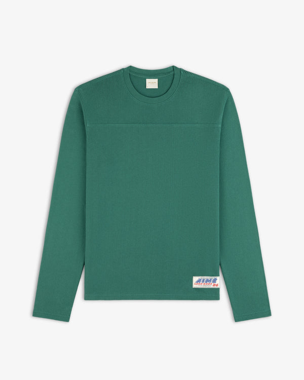 Long-sleeve mesh football tee with a textured pattern and a small white label at the bottom right.