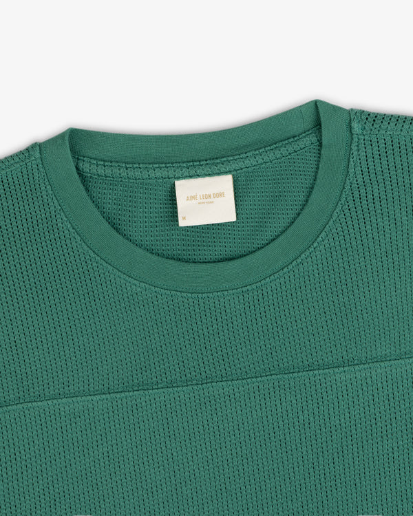 Long-Sleeve Mesh Football Tee in green, close-up of crew neck with textured fabric and white label at the collar.