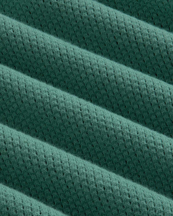 Close-up of the Long-Sleeve Mesh Football Tee’s green, ribbed fabric with diagonal lines and small perforations.