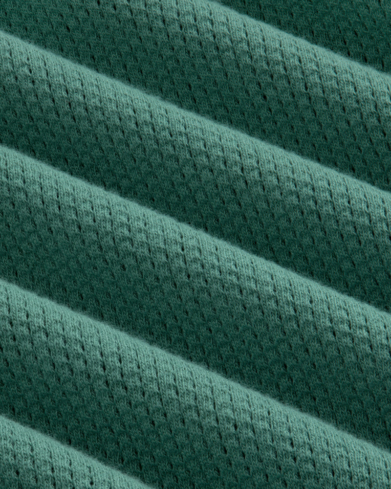 Close-up of the Long-Sleeve Mesh Football Tee’s green, ribbed fabric with diagonal lines and small perforations.