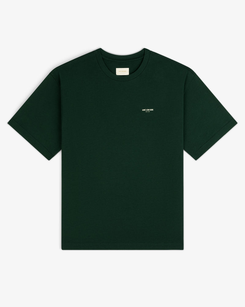 Micro Logo Tee in dark green with a small white chest label, shown on a white background.