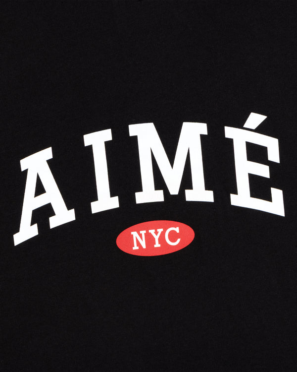 Aimé Souvenir Tee: White AIMÉ atop red oval with NYC in white, all set against a black background.