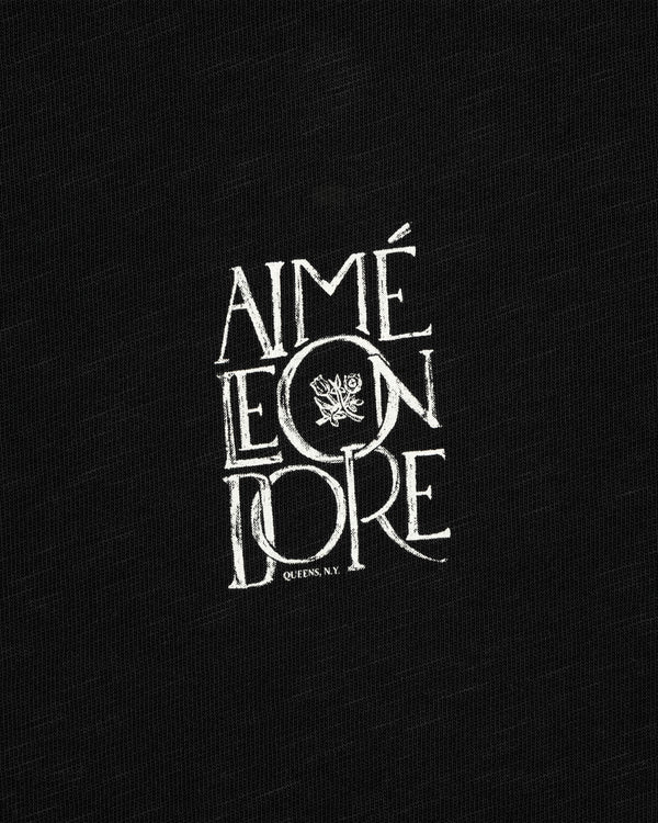 White “Stacked Logo” text with a crest features on black slub fabric background, Stacked Logo Slub Tee.
