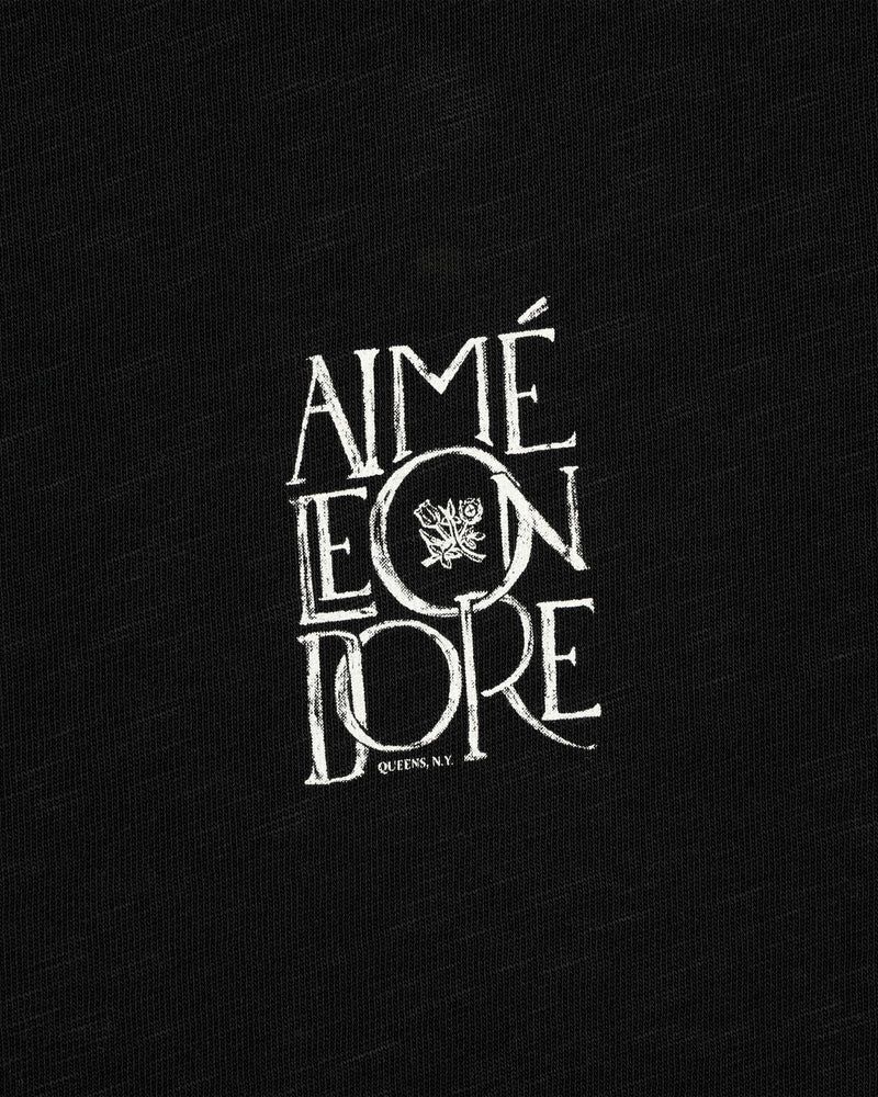 White “Stacked Logo” text with a crest features on black slub fabric background, Stacked Logo Slub Tee.