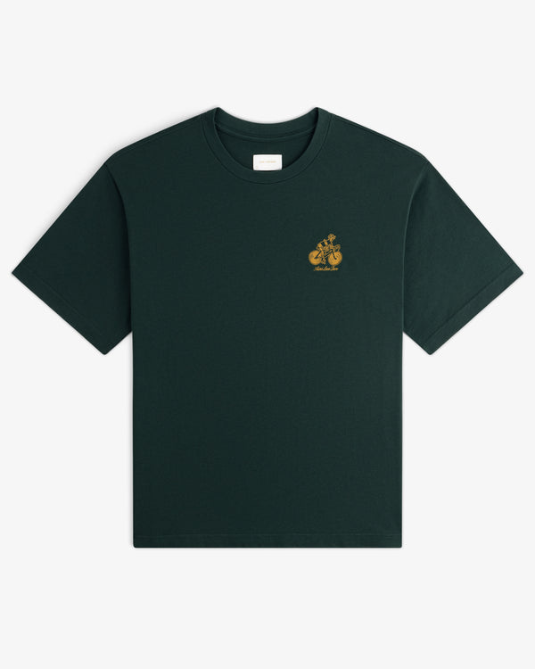 Aimé Tour Graphic Tee: Dark green short-sleeve t-shirt with a small yellow graphic and text on the left chest.