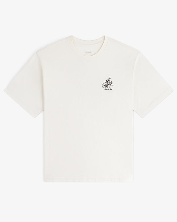 Aimé Tour Graphic Tee: White short-sleeve shirt with small black graphic and text on the left chest area.