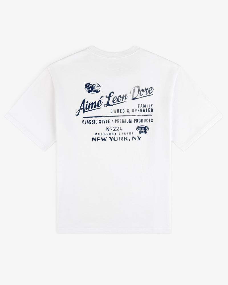Neighborhood Tee: White t-shirt with blue Aimé Leon Dore text and New York, NY address on the back.