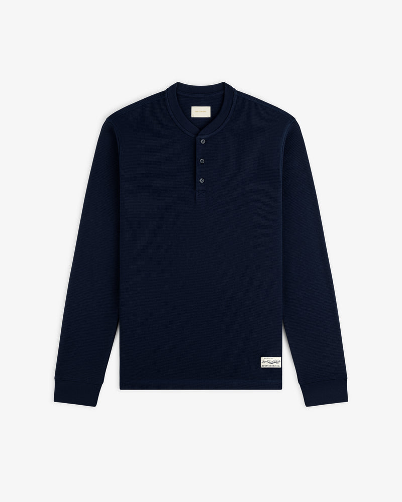 Navy blue Long-Sleeve Waffle Henley with a three-button placket and a small rectangular logo patch on the hem.