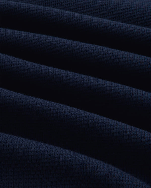 Close-up of a dark blue Long-Sleeve Waffle Henley with a waffle-knit texture and soft folds.